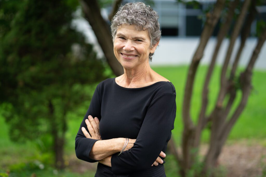 A photo of Fran Berman smiling at the camera. She's wearing a black top and standing in front of a blurred natural background.